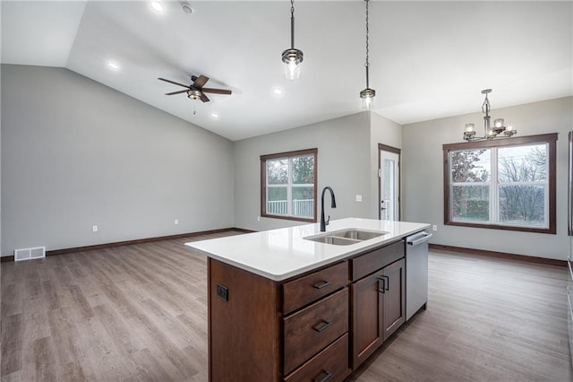 kitchen featuring pendant lighting, dishwasher, a center island with sink, sink, and vaulted ceiling