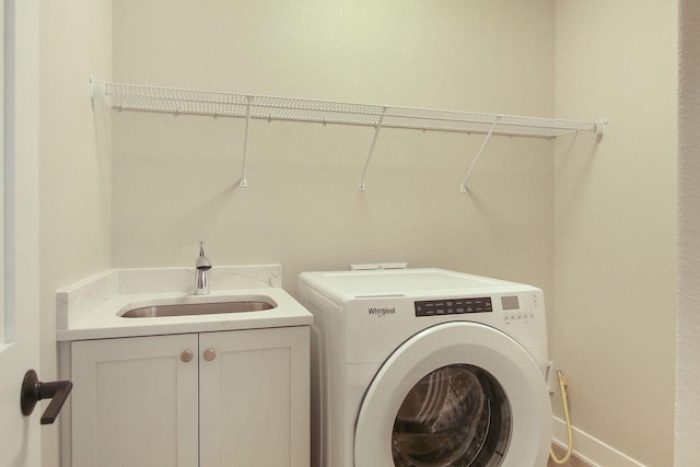 clothes washing area with separate washer and dryer, sink, and cabinets