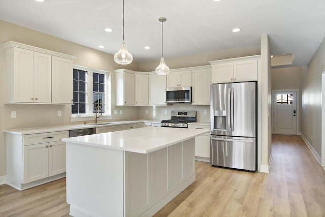 kitchen with white cabinets, hanging light fixtures, light hardwood / wood-style floors, a kitchen island, and stainless steel appliances