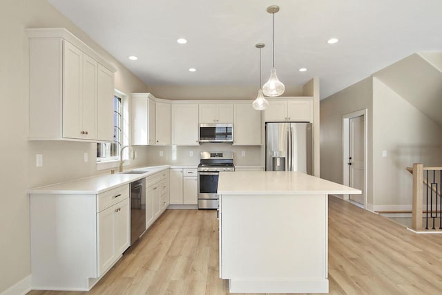 kitchen with white cabinets, appliances with stainless steel finishes, a kitchen island, and sink