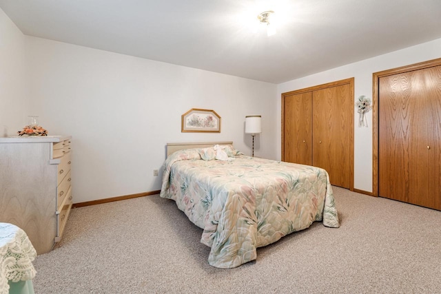 bedroom featuring light carpet and two closets