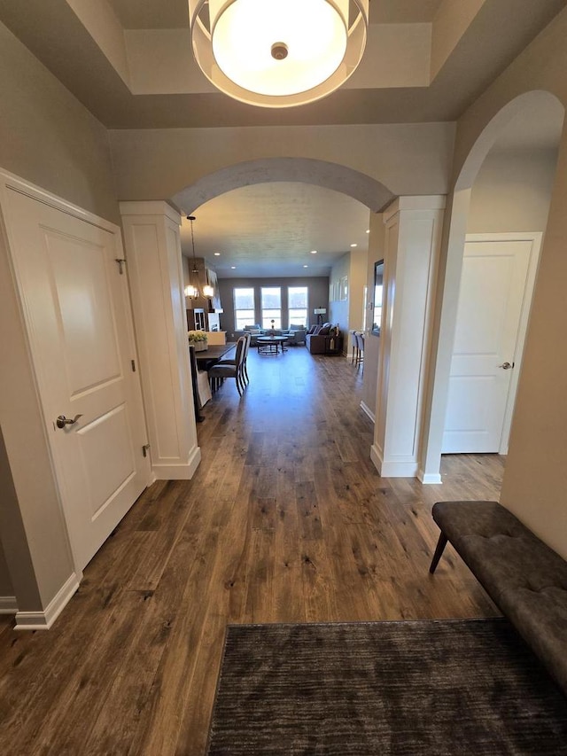 hall featuring a raised ceiling, dark hardwood / wood-style flooring, and a chandelier