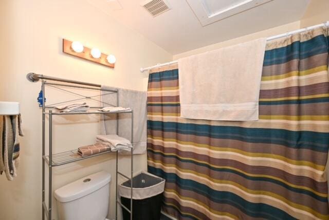 bathroom featuring a shower with shower curtain and toilet