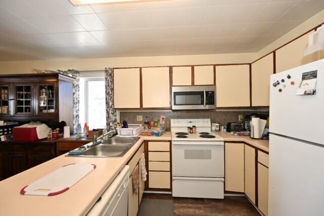 kitchen featuring cream cabinetry, white appliances, sink, and tasteful backsplash