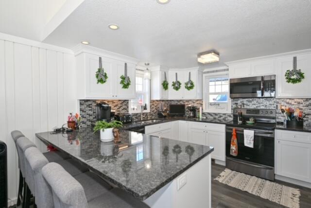 kitchen with white cabinets, appliances with stainless steel finishes, kitchen peninsula, and decorative backsplash