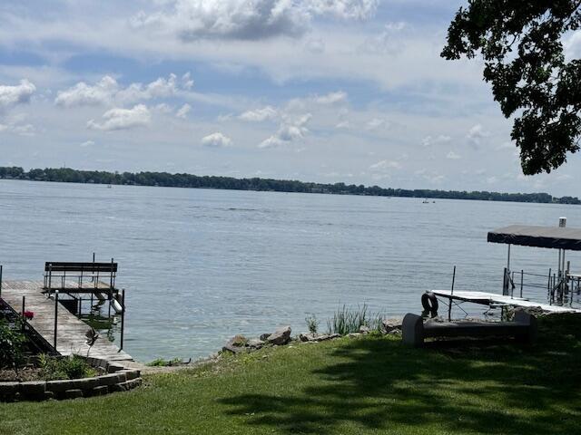 view of dock featuring a lawn and a water view