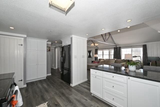 kitchen featuring white cabinets, dark hardwood / wood-style floors, black fridge, and vaulted ceiling