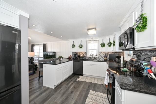 kitchen with black appliances, plenty of natural light, white cabinetry, and kitchen peninsula