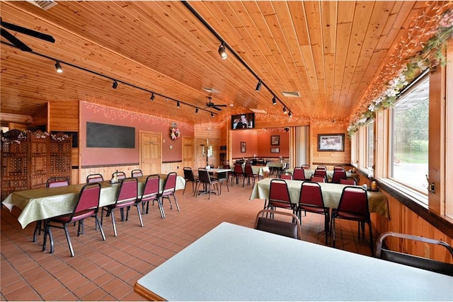 dining room featuring wood walls, lofted ceiling, track lighting, ceiling fan, and wood ceiling