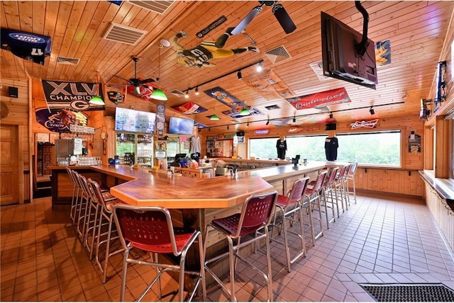 interior space with wood walls, wooden ceiling, track lighting, ceiling fan, and light tile patterned floors