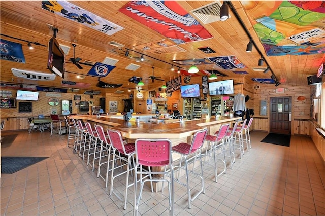 bar featuring butcher block counters, ceiling fan, rail lighting, wooden ceiling, and wooden walls