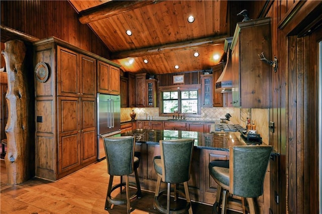 kitchen with a kitchen breakfast bar, kitchen peninsula, high end fridge, and light hardwood / wood-style flooring