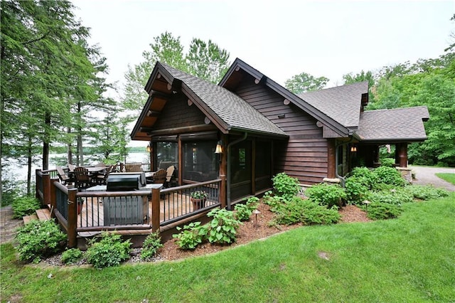 rear view of house featuring a sunroom and a yard