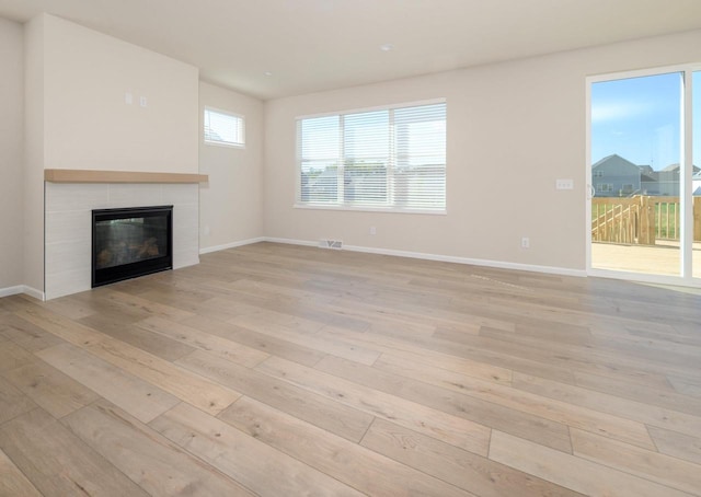 unfurnished living room featuring light hardwood / wood-style floors and a tiled fireplace