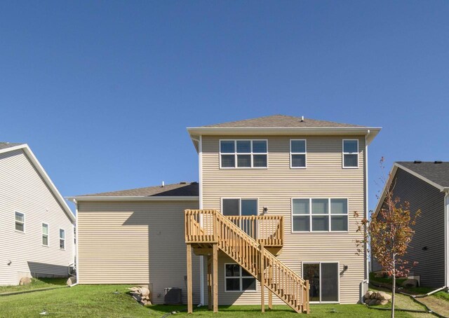 rear view of property with central AC unit, a wooden deck, and a lawn