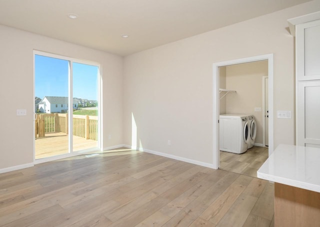 spare room with independent washer and dryer and light hardwood / wood-style floors