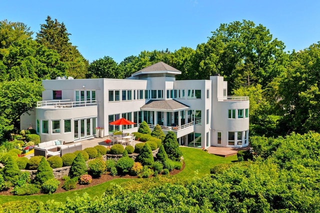 back of property with outdoor lounge area, a patio area, and a balcony