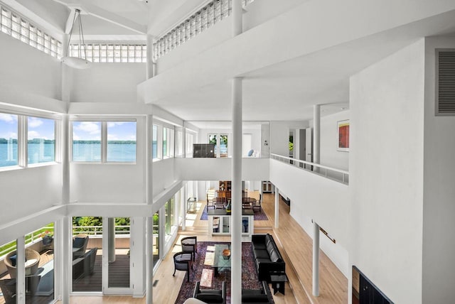 living room featuring a towering ceiling, a water view, and hardwood / wood-style flooring