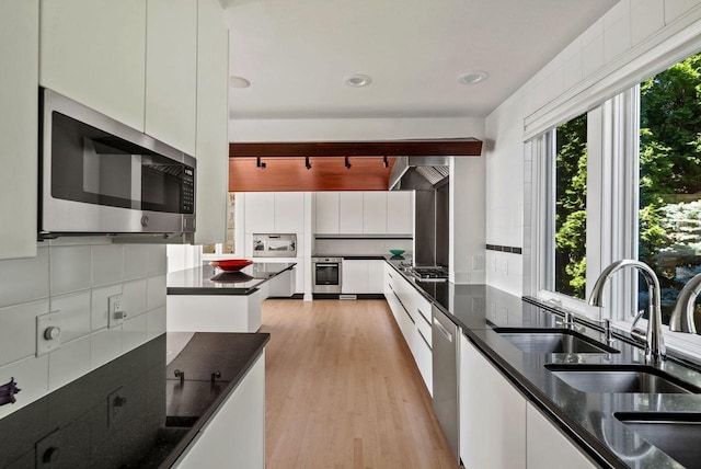 kitchen featuring decorative backsplash, white cabinets, stainless steel appliances, and light hardwood / wood-style floors