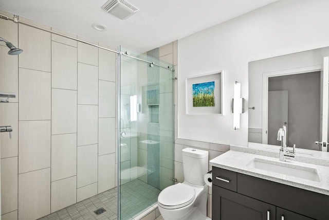 bathroom with tile patterned floors, an enclosed shower, vanity, tile walls, and toilet