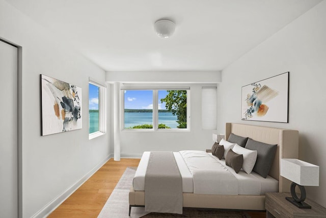 bedroom featuring a water view and light hardwood / wood-style floors