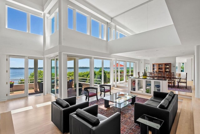 living room featuring plenty of natural light, a water view, and a high ceiling