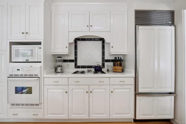 kitchen with white cabinets, decorative backsplash, and built in appliances