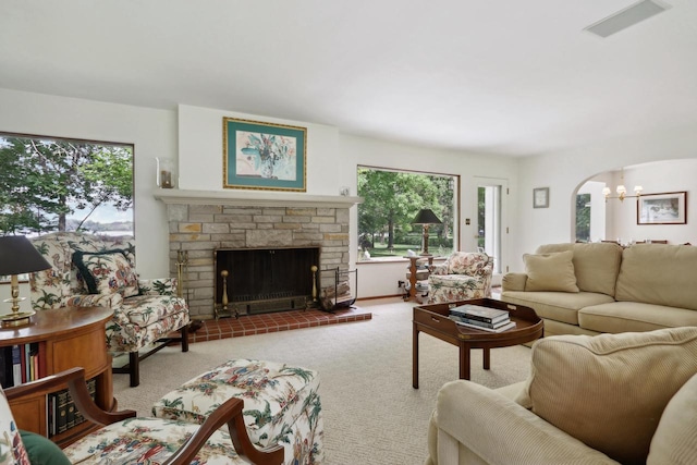 living room featuring a fireplace, a chandelier, a healthy amount of sunlight, and light colored carpet