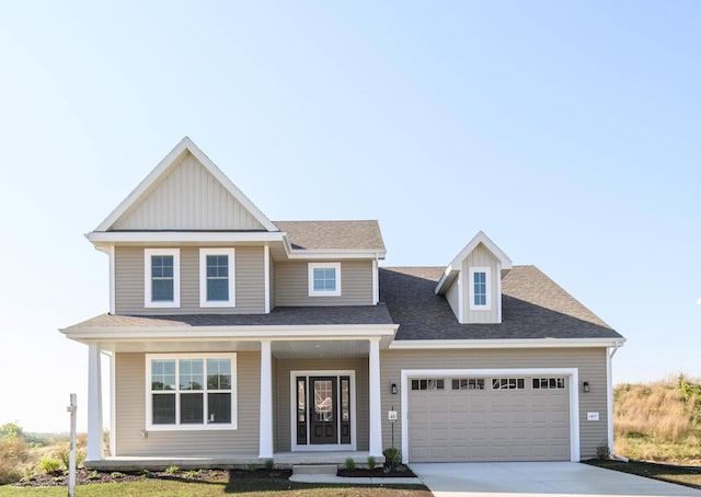 view of front of home featuring covered porch, a garage, and a front yard