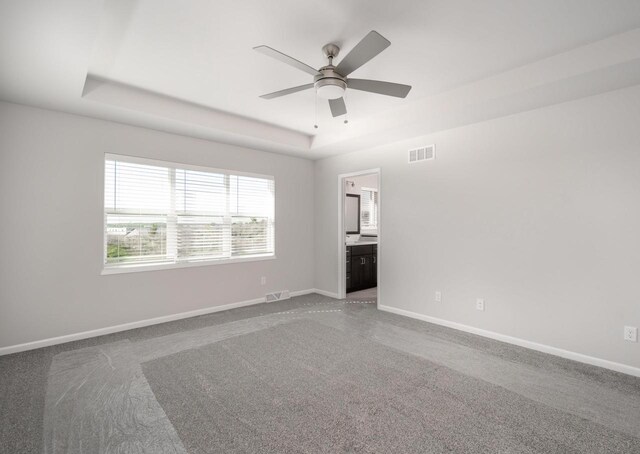 spare room with carpet flooring, a tray ceiling, and ceiling fan