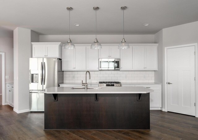 kitchen featuring pendant lighting, sink, stainless steel appliances, and a kitchen island with sink