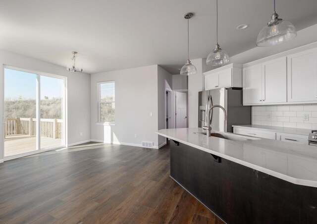 kitchen with decorative backsplash, stainless steel fridge, sink, decorative light fixtures, and white cabinets