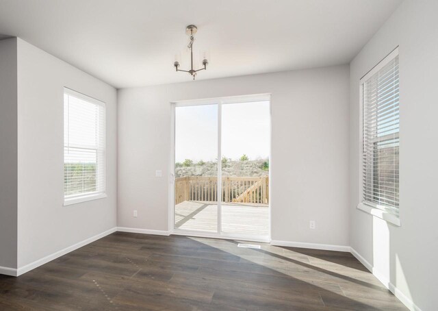 unfurnished dining area featuring dark wood-type flooring and a notable chandelier