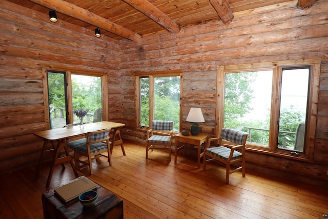 sitting room with rustic walls, a wealth of natural light, beamed ceiling, and wood ceiling