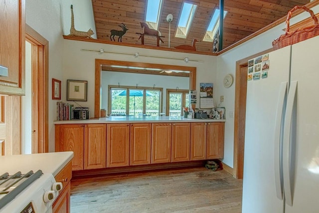 kitchen with white fridge, vaulted ceiling with skylight, wooden ceiling, and light hardwood / wood-style flooring