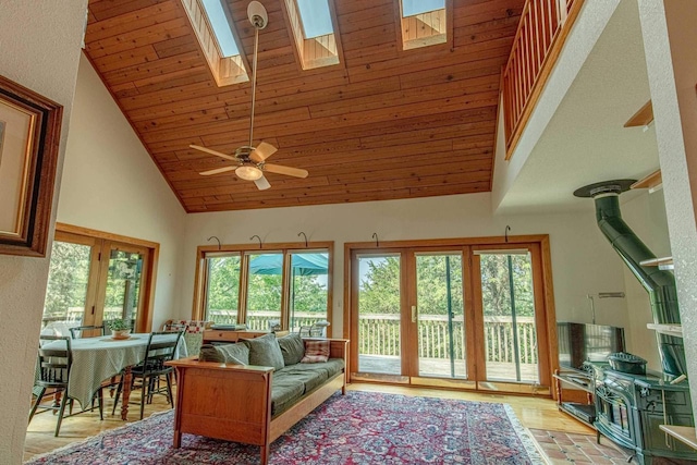 living room with ceiling fan, a skylight, high vaulted ceiling, light hardwood / wood-style floors, and wooden ceiling