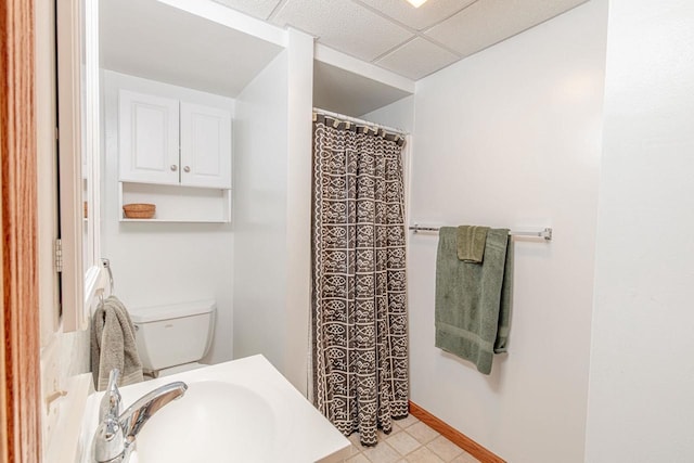 bathroom featuring a drop ceiling, sink, and toilet