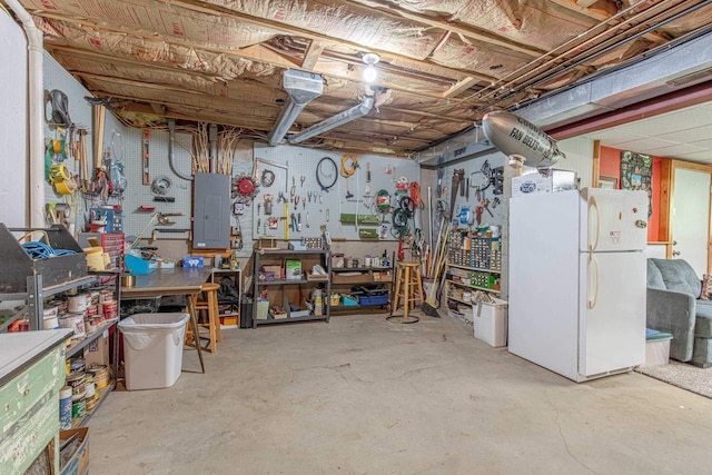 basement with white fridge, electric panel, and a workshop area