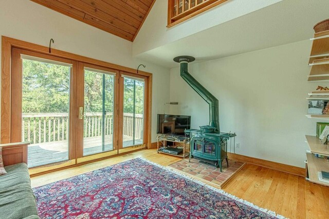 entryway with lofted ceiling, hardwood / wood-style floors, wood ceiling, and a wood stove