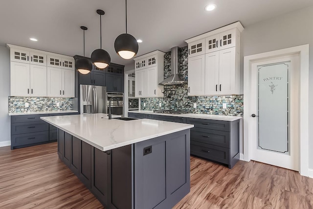 1421 Greenleaf Ct, Sun Prairie, WI 53590 - kitchen with wall chimney range hood, stainless steel appliances, a sink, tasteful backsplash, and an island with sink