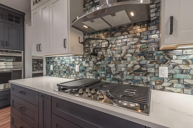 1421 Greenleaf Ct, Sun Prairie, WI 53590 - kitchen with range hood, appliances with stainless steel finishes, backsplash, and white cabinetry