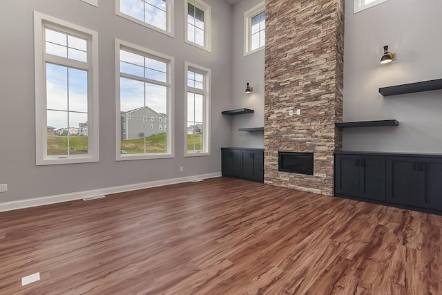 1421 Greenleaf Ct, Sun Prairie, WI 53590 - unfurnished living room with wood finished floors, a high ceiling, baseboards, and a stone fireplace