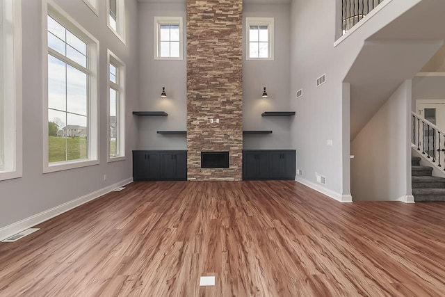 1421 Greenleaf Ct, Sun Prairie, WI 53590 - unfurnished living room with a high ceiling, wood finished floors, stairs, baseboards, and a stone fireplace