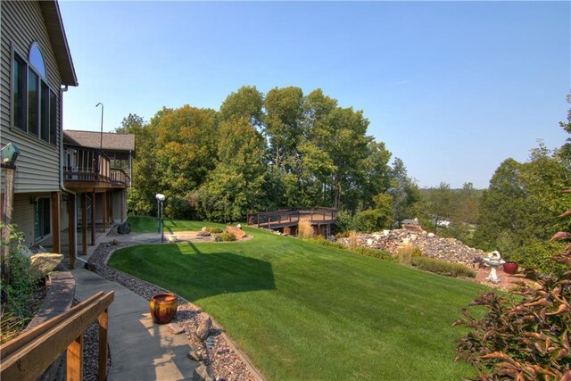 rear view of house featuring a lawn, a sunroom, and a deck