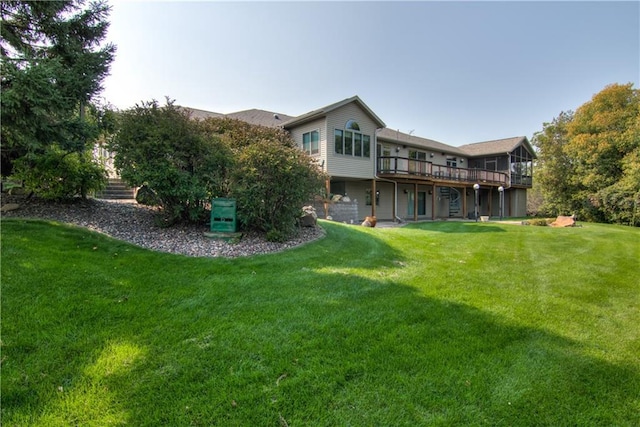 rear view of house featuring a wooden deck and a lawn