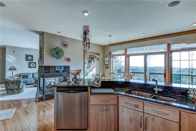 kitchen with stainless steel dishwasher, dark stone counters, sink, light brown cabinets, and hanging light fixtures