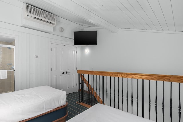 tiled bedroom with a wall mounted air conditioner, ensuite bath, beam ceiling, wooden ceiling, and a closet