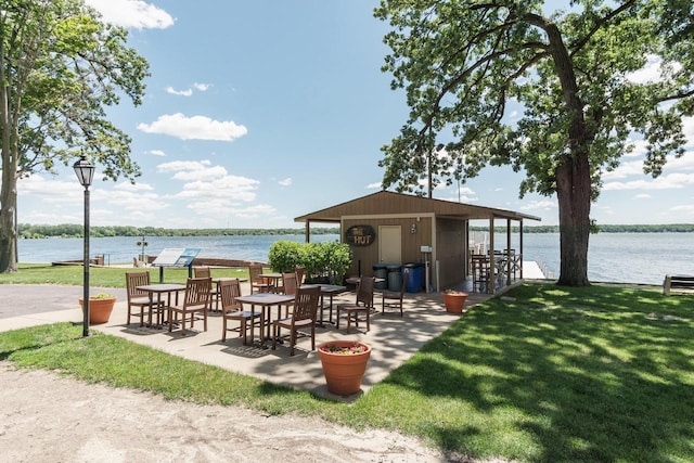 view of community featuring a water view, a shed, and a lawn