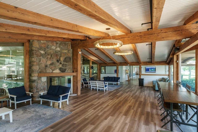 interior space with hardwood / wood-style floors, lofted ceiling with beams, a stone fireplace, and a chandelier