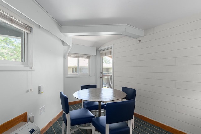 dining area with beamed ceiling and wooden walls